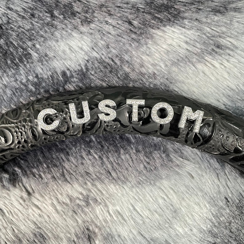 Peut inclure: Volant de direction en cuir noir avec un design personnalis&eacute; et le mot "CUSTOM" &eacute;crit en strass argent&eacute;s.