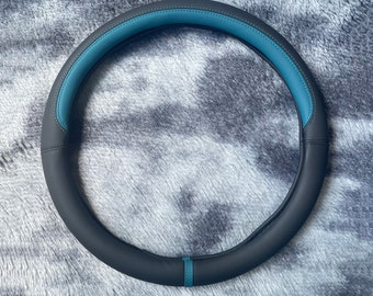 Può includere: Un coprivolante in pelle nera con una striscia di accento blu.