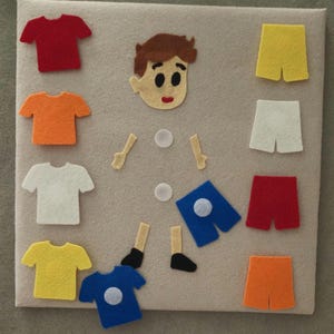 May include: A felt board with a boy's face, arms, legs, and various colored shirts and shorts. The shirts are red, orange, white, yellow, and blue. The shorts are yellow, white, red, and orange. The board is beige.