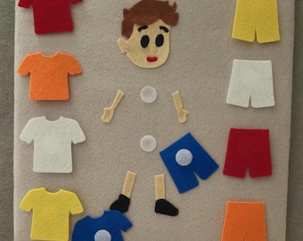 May include: A felt board with a boy's face, arms, legs, and various colored shirts and shorts. The shirts are red, orange, white, yellow, and blue. The shorts are yellow, white, red, and orange. The board is beige.