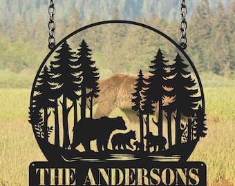 May include: Black metal silhouette of a family of bears walking through a forest with a circle around them. The text "THE ANDERSONS" is on a separate black metal sign below the circle.