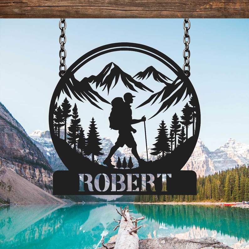 May include: Black metal silhouette of a hiker with a backpack walking through a mountain landscape. The silhouette is in a circle with the name "ROBERT" below it.