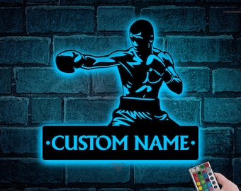 May include: A blue neon sign with a silhouette of a boxer throwing a punch. The sign has a customizable nameplate that reads "CUSTOM NAME". The sign is illuminated with a blue light and comes with a remote control for changing the color of the light.