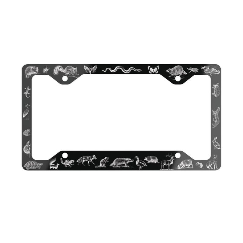 May include: Black metal license plate frame with a white outline and various animal illustrations, including a snake, a butterfly, a turtle, a deer, and a bird.