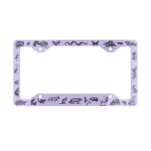 May include: A lavender-colored license plate frame with a black and white illustration of various animals around the border. The animals include a snake, a butterfly, a squirrel, a turtle, a bird, a deer, a rabbit, and a mouse.