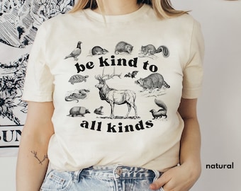 Könnte beinhalten: Ein weißes T-Shirt mit einer schwarzen Grafik verschiedener Tiere und dem Text "be kind to all kinds".