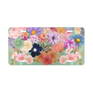May include: A green background with a colorful floral arrangement of pink, purple, blue, yellow, orange, and red flowers. The flowers are arranged in a heart shape.
