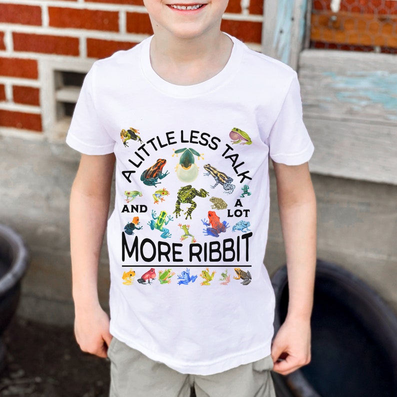 K&ouml;nnte beinhalten: Wei&szlig;es T-Shirt mit einem Kreisdesign mit Fr&ouml;schen und dem Text "A little less talk and a lot more ribbit".