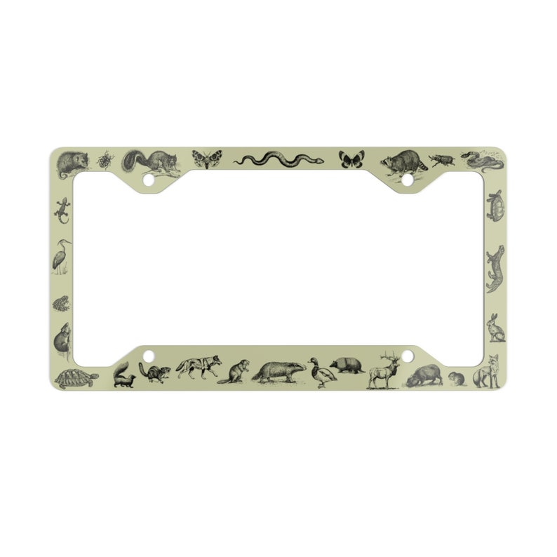 May include: A light green metal license plate frame with a black and white illustration of various animals, including a snake, a butterfly, a turtle, a squirrel, a deer, a bird, and a raccoon.