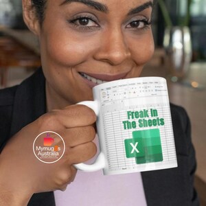 May include: White ceramic mug with a green and white design featuring a spreadsheet with the text "Freak In The Sheets" and a green "X" button.