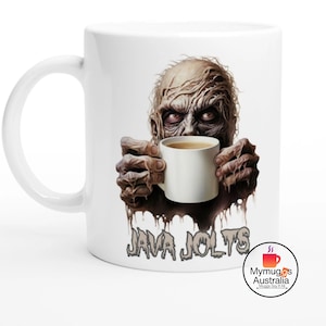 May include: White ceramic coffee mug featuring a zombie-like figure holding a white coffee cup. The mug has the text "Java Jolts" printed on it.