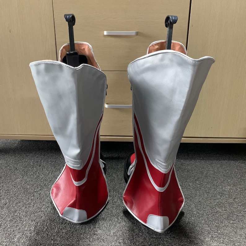 K&ouml;nnte beinhalten: Ein Paar rot-wei&szlig;e Stiefel mit einem wei&szlig;en Lederoberteil und roten Akzenten. Die Stiefel haben eine spitze Zehenpartie und einen hohen Absatz.