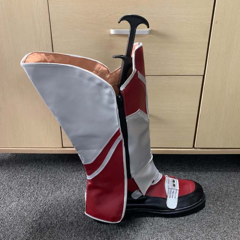 K&ouml;nnte beinhalten: Ein Paar rot-wei&szlig;e Stiefel mit schwarzer Sohle. Die Stiefel haben einen Rei&szlig;verschluss an der Seite und einen wei&szlig;en Riemen &uuml;ber dem Oberteil.