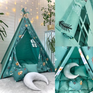 Könnte beinhalten: Ein blaugrünes Tipi-Zelt für Kinder mit einem Waldtier-Druck. Das Zelt hat ein Fenster und ist mit Kissen und einem sichelförmigen Kissen dekoriert.