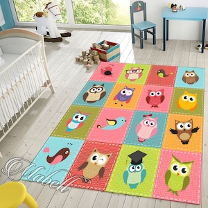 May include: A colourful rug with a patchwork design featuring owls and birds. The rug has a light blue, pink, green, yellow, and red colour scheme. The owls are all different colours and have different expressions. The birds are all different colours and have different designs.