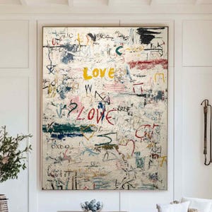 May include: Large abstract painting with the word "LOVE" in red and yellow, along with other colorful scribbles and markings. The artwork is displayed in a bright, modern living room setting.