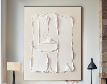 May include: A white abstract painting with textured brushstrokes in a black frame hangs on a white wall above a wooden shelf with vases and a bowl. The painting is in a living room with a couch, a lamp, and a fireplace.