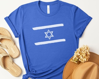 Könnte beinhalten: Ein königsblaues T-Shirt mit einer weißen Grafik des israelischen Flagge. Die Flagge zeigt einen weißen Davidstern auf blauem Hintergrund mit zwei weißen Streifen.