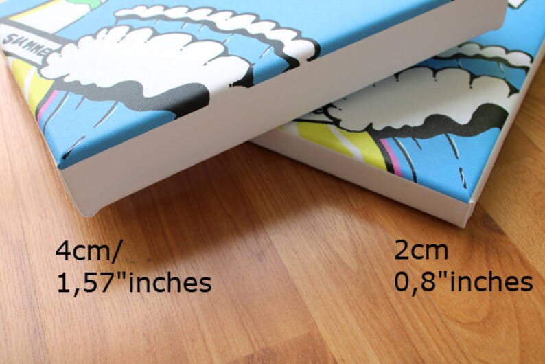 Op de afbeelding: Twee canvasdoeken met witte frames, een is blauw met witte wolken en de tekst "SUMMER" en de andere is blauw met gele en roze accenten. Het canvasdoek links meet 4 cm of 1,57 inch en het canvasdoek rechts meet 2 cm of 0,8 inch.