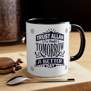 Puede incluir: Taza de cerámica blanca con interior y asa negros. La taza presenta el texto "TRUST ALLAH TO MAKE TOMORROW A BETTER DAY" en azul marino. Diseños decorativos tipo mandala en los laterales.