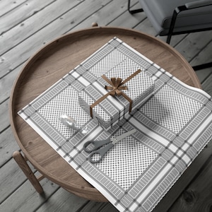 May include: A brown wooden tray with a white and black patterned wrapping paper. A gift box wrapped in the same paper is tied with a brown ribbon and a brown bow. A pair of silver scissors and a roll of tape are also on the tray.