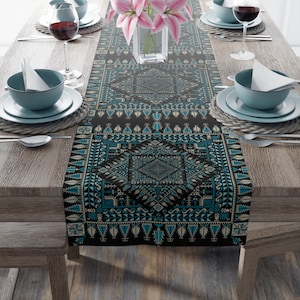 Può includere: Un runner da tavolo nero e blu con un motivo geometrico. Il runner è realizzato in tessuto e ha un bordo con frange.