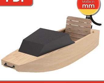 May include: A wooden model boat kit with a black fabric seat and a wooden back rest. The kit includes instructions and is designed to be built by hand. The text "Maße in mm" is visible on the image.