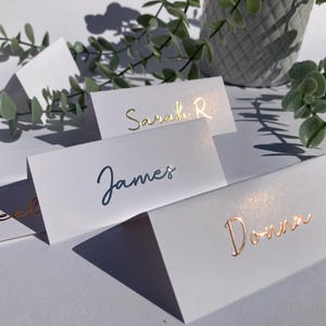 パーソナライズされた浮き彫りの箔押し結婚式またはパーティー名席札 | ゴールド、シルバー、またはローズゴールドの浮き彫り箔 | 手書きスタイル | 折りたたみ時 10cmx4.2 cm