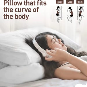 Puede incluir: Una almohada blanca con una mujer acostada sobre ella. La mujer lleva auriculares y gafas. La almohada est&aacute; dise&ntilde;ada para adaptarse a la curva del cuerpo. El texto "Pillow that fits the curve of the body" est&aacute; en la parte superior de la imagen. Los textos "Neck", "Legs" y "Back" est&aacute;n en la parte superior de la imagen con ilustraciones de c&oacute;mo usar la almohada para cada parte del cuerpo.