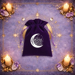 May include: A deep purple velvet drawstring pouch featuring a white graphic print of a crescent moon containing a cluster of crystals and small stars. The pouch has matching purple cord ties and is centred on a purple fabric surface.