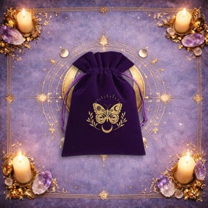 May include: A deep purple velvet drawstring pouch featuring a gold-coloured graphic of a butterfly with celestial symbols on its wings, including a sun and moon, flanked by leafy branches and a crescent moon positioned directly below the butterfly.