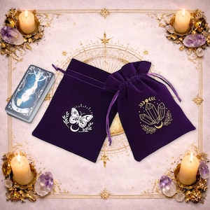 May include: Two deep purple velvet drawstring pouches featuring gold-coloured screen-printed designs. One pouch displays a butterfly with a crescent moon, while the other features a cluster of crystals with a moon phase cycle above it.