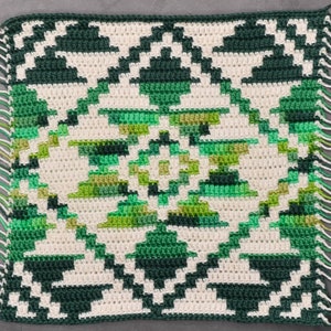May include: A green and white crocheted square with a geometric pattern and fringe on all sides.