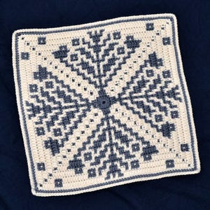 May include: A crocheted square with a geometric pattern in shades of gray and white.