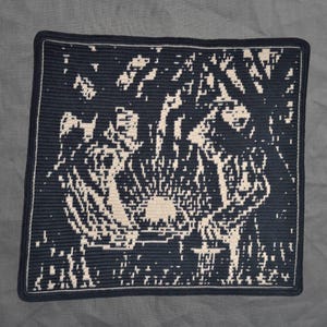 May include: A navy blue and cream crocheted blanket with a square shape. The blanket features an abstract design, possibly a landscape, with a navy border and a cream-colored edge. The design is intricate.