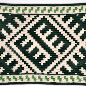 Puede incluir: Una manta de ganchillo hecha a mano con un patrón geométrico en verde oscuro y crema. El diseño incluye formas de diamante y un borde con detalles verdes. La manta está hecha con una puntada apretada, creando una superficie texturizada.
