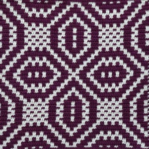 May include: Close-up of a woven textile with a repeating geometric pattern. The design features diamond shapes in a deep purple color, outlined and filled with white. The texture appears soft and detailed.