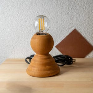 Lampada da tavolo. Realizzata in pino massello tornito. Grezza, pronta per essere dipinta. Misure: Altezza 30 cm. Diametro base: 12,5 cm. | Leroy Merlin