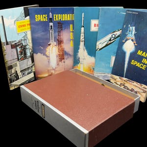 May include: A collection of five vintage Science Program booklets featuring space and technology themes, including titles like Space Exploration and Man in Space, displayed behind a rectangular brown and white storage box with a textured cover.