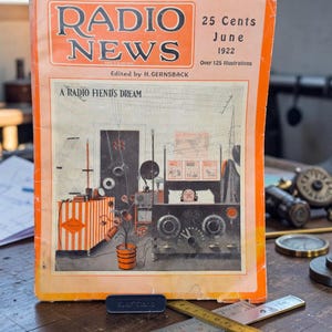 May include: A vintage June 1922 issue of Radio News magazine with an orange border. The cover features the title, the text A Radio Fiend's Dream, and an illustration of a person in bed with radio equipment. It measures approximately 8.5 inches wide.