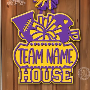 May include: A purple and yellow door hanger featuring a megaphone, pom-pom, and football helmet graphic above a sign with the text "TEAM NAME HOUSE". A purple and yellow ribbon bow is attached to the top. The text "Digital download SVG & DXF" is visible.