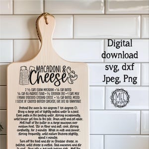 May include: A wooden chopping board with a recipe for macaroni and cheese. The recipe includes ingredients such as elbow macaroni, butter, flour, salt, milk, cheddar cheese, and crushed buttery crackers. The board has a handle and is decorated with a grater and a wedge of cheese.