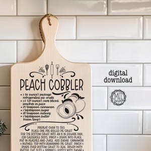 May include: A light-colored wooden cutting board featuring a black printed recipe for peach cobbler, including ingredients like 15 ounce pie crusts and 29 ounce cans of peaches, with instructions for baking at 350 degrees in an 8 inch square pan.