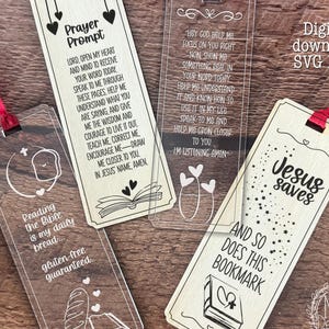 Könnte beinhalten: Vier transparente Acryl-Lesezeichen mit roten Bändern. Ein Lesezeichen hat den Text "Prayer Prompt", ein anderes lautet "Jesus saves and so does this bookmark". Die anderen beiden haben religiöse Zitate und Illustrationen.