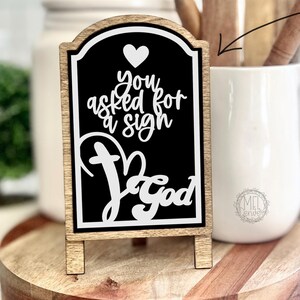 Puede incluir: Un letrero en blanco y negro con el texto "You asked for a sign, God" en un marco de madera. El letrero está sobre una mesa de madera. Esta publicación es solo para el inserto del letrero. El marco se vende por separado.