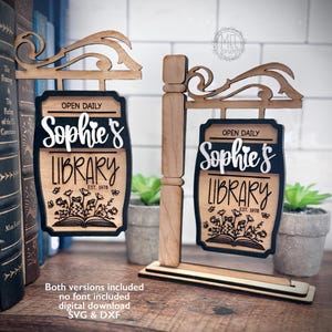 May include: Wooden library sign with the words "Sophie's Library" in a decorative font. The sign includes the words "Open Daily" and "Est. 1978". The sign has a black border and a floral design. The sign is made of wood.