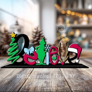 Peut inclure: Une enseigne décorative affichant le mot "Believe" dans une police stylisée. La lettre B est un sapin de Noël vert avec une étoile jaune, le e est rouge avec un nœud bleu, le l est un personnage vert, le i est un flocon bleu, le e est rouge avec une boule verte, le v est des bois de renne marron, et le e est noir avec un bonnet de Père Noël rouge.