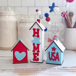 May include: Three wooden house-shaped decorations in red, white, and blue. One says "HOME" with a star, another has a heart, and the third says "USA" with a star. The text "Digital download / laser ready file" is at the bottom.