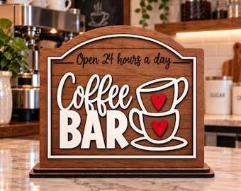 May include: A wooden sign with a dark brown finish featuring the text "Open 24 hours a day" and "Coffee BAR" in white lettering. The design includes a graphic of two stacked white coffee cups, each decorated with a small red heart in the centre.