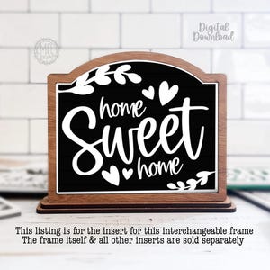 May include: Wooden framed sign with a black background and the words "home sweet home" in white script. The sign has a decorative leaf and heart design. The sign is on a wooden base.